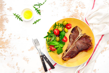 T-bone steak ready to eat, served on a plate, view from above