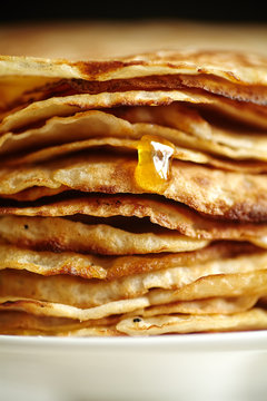 Close up image of crepes cake with orange jam and honey on white cake stand. Pancake breakfast concept