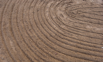 Naklejka premium Circles on sand. Sand with oval lines. Sand pictures on the beach. Close up of sand with lines