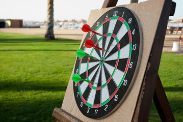 Close up of darts with red and green arrows on green grass background. Darts game on vacation....