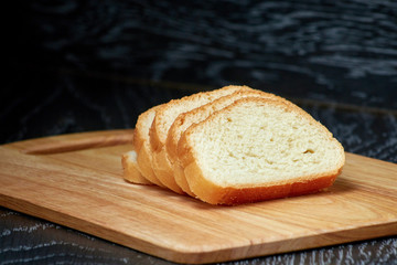 Sliced bread on wooden cutting Board, on dark wooden background, bran