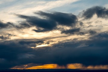 Fototapeta premium Dramatic even clouds with snow showers falling out and orange sky