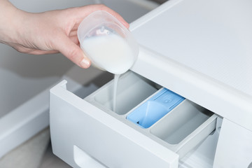 hand pours a greasy detergent into the washing machine compartment