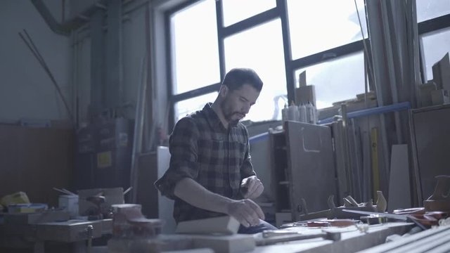 Handsome man in his fourties working with wood in his workshop