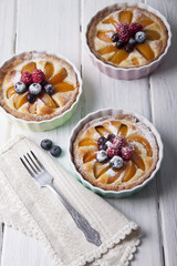 Tarts with curd cream, apricot and berries in ceramic form