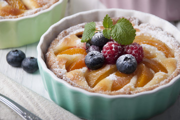 Tart with curd cream, apricot and berries in ceramic form