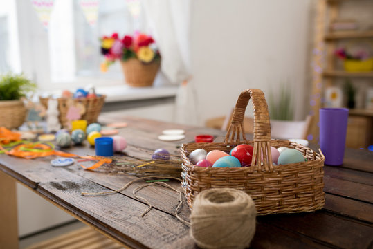 Background image of wicker basket with Easter eggs on wooden table in crafting workshop set for set for making decorations, copy space