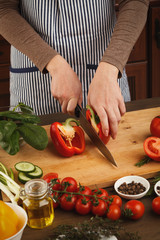 Preparing fresh vegetable salad at kitchen table