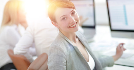 rear view. beautiful business woman sitting near the desktop and looking at the camera.