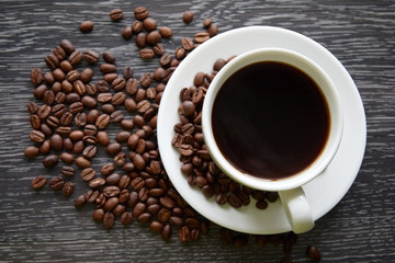 White Cup of black hot coffee with coffee beans on dark wood background
