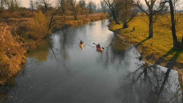 Aerial shot of two kayaks going down the river in in amazing landscape on a beautiful autumn sunny day.
