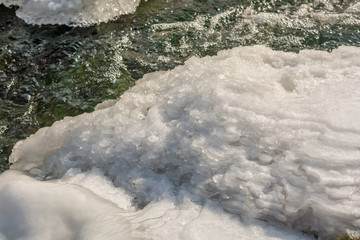 Wasser eines Baches gefriert Schicht f&uuml;r Schicht am Bachrand