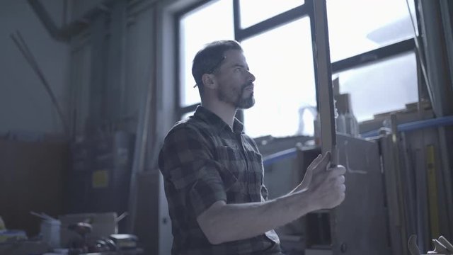 Handsome man in his fourties working with wood in his workshop
