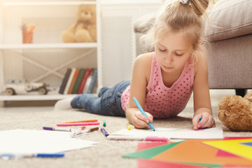 Smiling little girl drawing with colored pencils at home