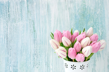 Pink and white tulips bouquet in white vase on light blue background. Holiday background, copy space. Valentine Day, Mothers day, birthday concept.