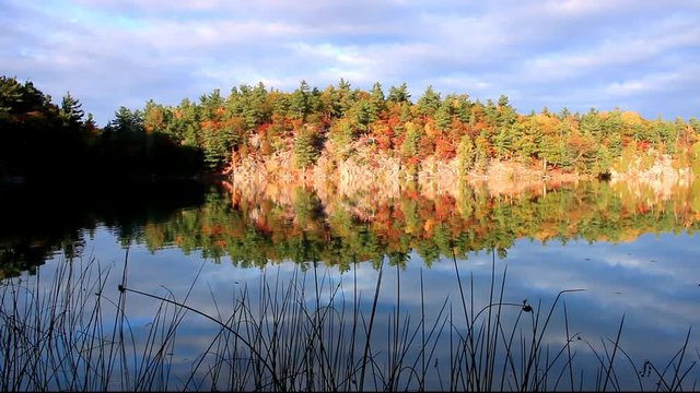 Fall colors and reflections on water in Gatineau Park in a beautiful autumn afternoon
