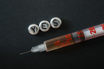 syringe with liquid on a dark background, macro, letters are laid out, yes