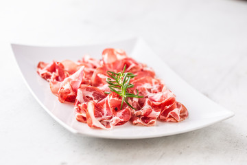 Prosciutto. Curled slices of delicious italian prosciutto with rosemary
