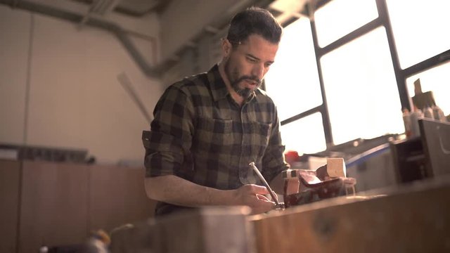 Handsome man in his fourties working with tools and wood at his workplace