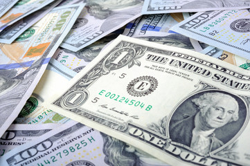 macro shot, background of dollar bills, on top is a one dollar dollar note