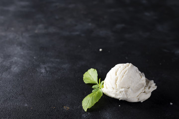 vanilla ice cream ball with green leaves on dark