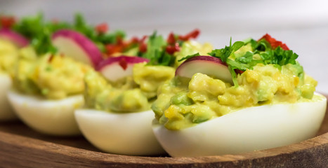 Boiled eggs stuffed with avocado paste with parsley, chili and radish - healthy breakfast- macro