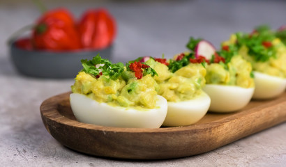 Boiled eggs stuffed with avocado paste with parsley, chili and radish - healthy breakfast- macro