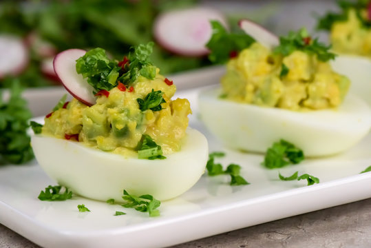 Boiled eggs stuffed with avocado paste with parsley, chili and radish - healthy breakfast- macro