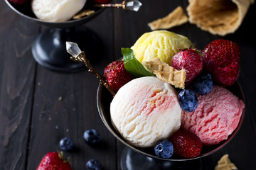 Bowl with ice cream with three different scoops of white, yellow, red colors and waffle cone