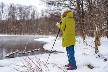 Woman Amateur photographer takes a winter landscape on the lake in the forest. copy space