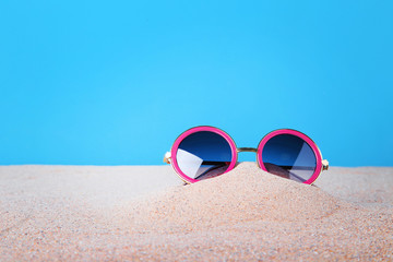 Obraz premium Pink sunglasses on the beach sand