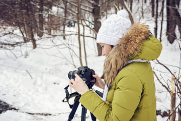 Woman Amateur photographer takes a winter landscape on the lake in the forest. copy space
