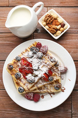 Sweet waffle with berries on brown wooden table
