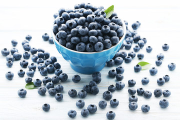 Ripe blueberries in bowl on white wooden table