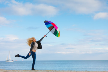 Woman jumping with colorful umbrella on beach