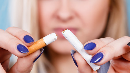 Obraz na płótnie Canvas Woman breaking cigarette, getting rid of addiction