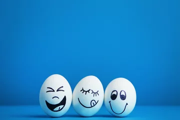 Zelfklevend Fotobehang Eggs with funny faces on blue background © 5second