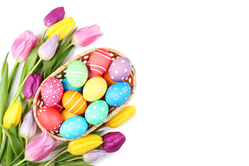 Fototapeta na wymiar Colorful easter eggs in basket with tulips on white background