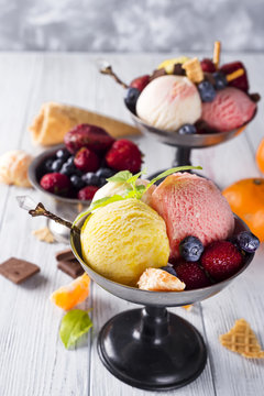 Bowl with ice cream with three different scoops of yellow, red colors and waffle cone, chocolate,