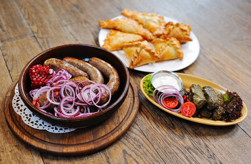 appetizing fried sausages against the background of samsa and dolma. Georgian and Caucasian cuisine