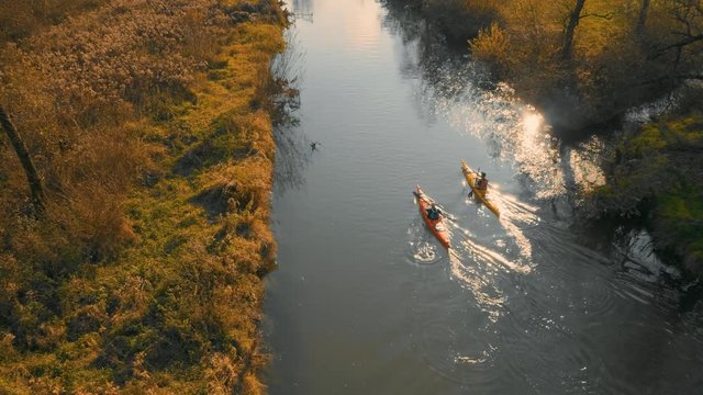 Aerial lift of two kayaks going up the river in in amazing landscape on a beautiful autumn sunny day.
