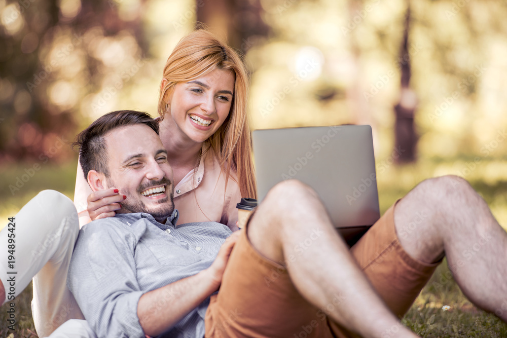 Wall mural young couple using laptop in the park