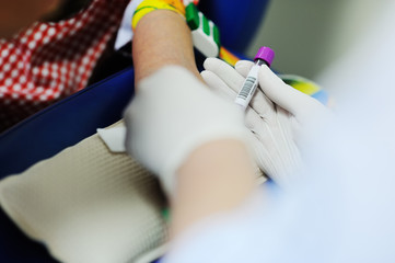 a doctor or nurse takes blood from a vein in a child of a boy. Blood chemistry