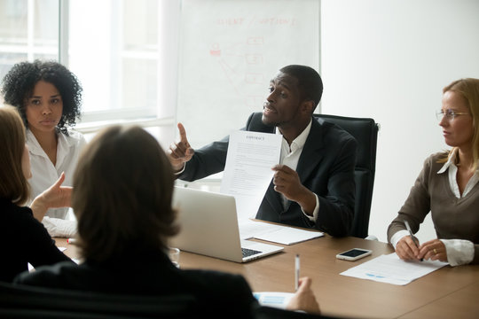 African american businessman disagreeing with contract terms at group multi-ethnic negotiations, black partner arguing about deal conditions or fraud scam pointing at document at multiracial meeting