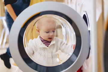 The baby looks through the window of the washing machine