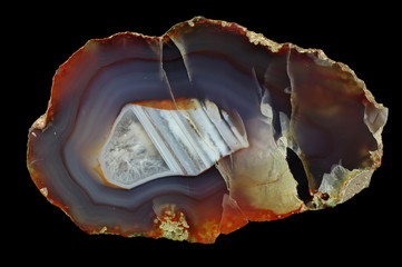 Fototapeta premium Cross section of agate. Multicolored silica rings colored with metal oxides are visible. Horizontal agate, filled with quartz (in reverse position). Origin: Rudno near Krakow, Poland.