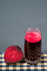 Natural juice from beets. The juice is poured into a clear glass, which stands on the tablecloth.