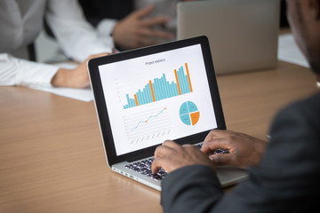 African businessman working on computer analyzing project statistics planning corporate strategy at...