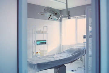 operating room and surgical lamp in a modern clinic through an open door