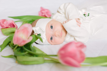 Little beautiful newborn girl lying on the bed among the flowers